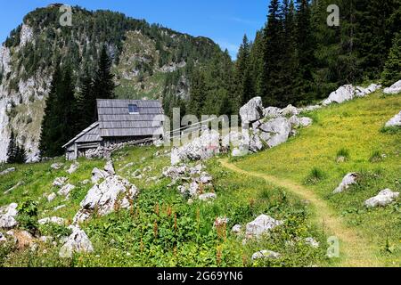 Capanne Pastore a Planina Visevnik e segno per planina Ovcarija su una roccia nelle colline sopra Bohinj, Slovenia Foto Stock