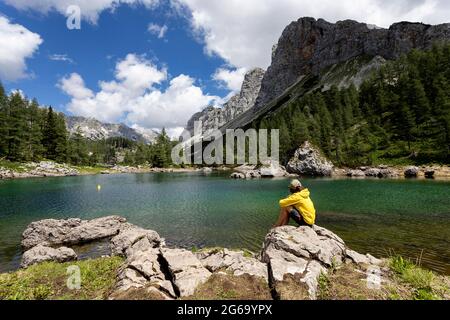 Ragazzo seduto sulla roccia al lago doppio nella valle dei laghi del Triglav. Slovenia Foto Stock