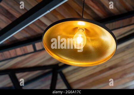 lampada calda nella struttura sotto il tetto è decorata con legno nel cantiere di una casa Foto Stock