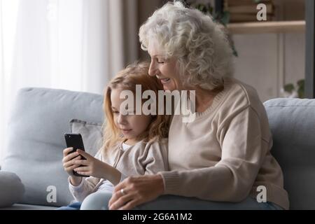 Presteen ragazza nonkid mostrare più vecchio nonna divertente foto sul telefono Foto Stock
