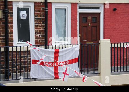 Londra, Regno Unito. 04 luglio 2021. Una bandiera di St George su una ringhiera vicino alla porta di un residente nella tenuta di Kirby. Kirby Estate a Bermondsey, è coperto con oltre 400 bandiere di San Giorgio a sostegno della squadra inglese per il ritardato torneo di calcio Euro 2020. Una tradizione da parte dei residenti della tenuta dal 2012.la squadra inglese ha battuto l'Ucraina 4-0 a Roma il 3 luglio facendo alla semifinale contro la Danimarca, che è in programma il 6 luglio a Wembley. Credit: SOPA Images Limited/Alamy Live News Foto Stock