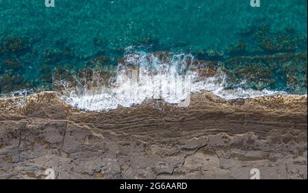 Panorama aereo della costa rocciosa con onde infrangenti vicino a Pomos, Cipro Foto Stock