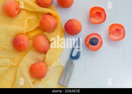 Deliziose albicocche con coltello piccolo sul tavolo da primo piano. Vista orizzontale dall'alto con tovagliolo giallo. Foto Stock