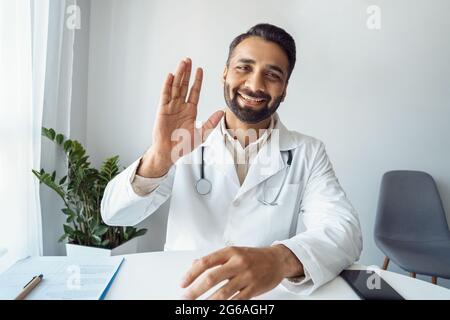 Ritratto headshot di positivo sorridente medico indiano uomo in uniforme dire hi Foto Stock