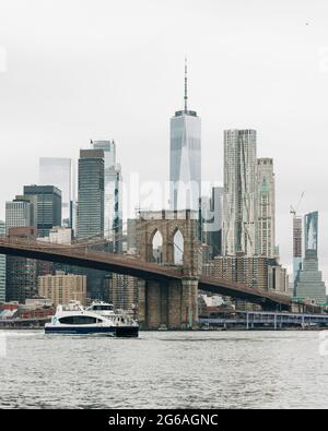 Un traghetto con il Ponte di Brooklyn e lo skyline di Manhattan sullo sfondo, da Dumbo, Brooklyn, New York City Foto Stock