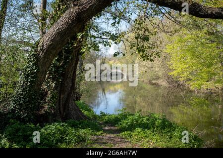 Vecchio ponte di pietra su un piccolo fiume tranquillo, preso in primavera in una giornata di sole a Brunoy (vicino a Parigi), Francia Foto Stock