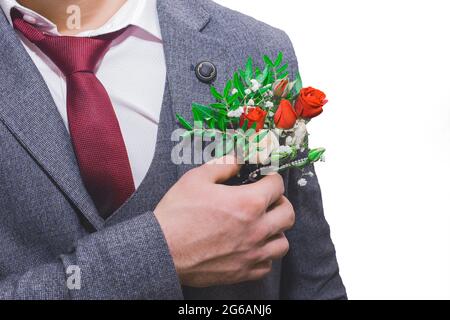 La mano dello sposo al matrimonio corregge il primo piano del boutonnière. Foto Stock