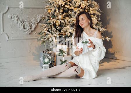 Donna graziosa che tiene i regali di Natale vicino albero decorato Foto Stock