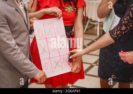 Un gruppo di persone gioca il gioco di croci e zeri su un grande foglio bianco di carta. Foto Stock