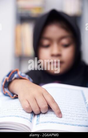 Piccola ragazza musulmana in hijab legge Quran Foto Stock