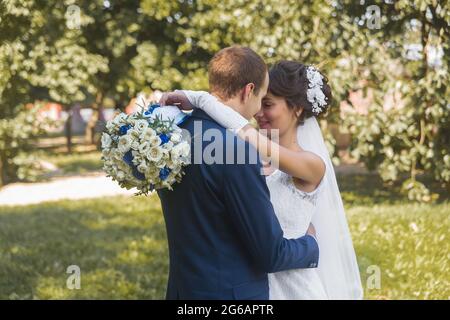 Bielorussia, regione di Minsk - 11 agosto 2018: Matrimonio. Gli abbracci e la tenerezza della sposa felice e sposo su una passeggiata nello sfondo del parco all'aperto. Foto Stock