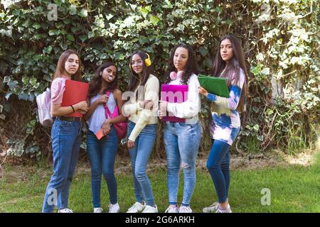 Ritratto di ragazze adolescenti con i loro zaini e notebook guardando la macchina fotografica in un giardino verde Foto Stock