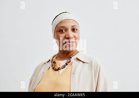Ritratto minimo di donna afroamericana sorridente guardando la macchina fotografica mentre si trova su sfondo bianco, copia spazio Foto Stock