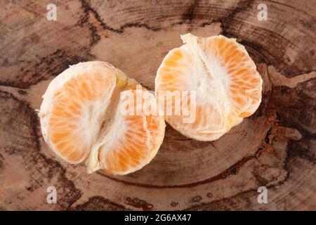 Frutta tangerina matura sbucciata e aperta su rustico sfondo di legno Foto Stock