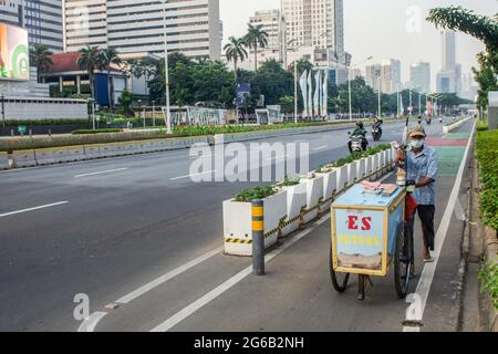 Un venditore di strada tira il carrello su una strada vuota durante l'imposizione delle restrizioni di emergenza. L'Indonesia ha imposto restrizioni alle attività comunitarie di emergenza, localmente note come PPKM, a Java e Bali dal luglio 3-20 per frenare l'epidemia di Covid-19 del paese dopo che la precedente politica di micro PPKM si è rivelata inefficace. Il Ministero della Salute ha detto sabato che l'Indonesia ha registrato 27, 913 casi recentemente confermati di Covid-19 nelle ultime 24 ore, il picco più alto giornaliero, portando il totale a 2, 256, 851, dal momento che il primo caso è stato rilevato nel marzo 2020. (Foto di Agung Fatma Putra/SOPA im Foto Stock