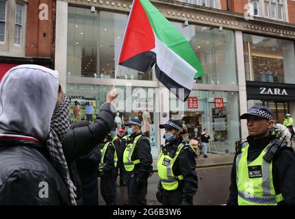 Londra, Regno Unito. 23 maggio 2021. Durante la protesta un manifestante ha ondato una bandiera palestinese verso i sostenitori israeliani dell'altra parte del cordone di polizia.i dimostranti pro-israeliani si radunano fuori dall'ambasciata israeliana di High Street Kensington a sostegno del cessate il fuoco concordato il 21 maggio. Un piccolo gruppo di palestinesi si è rivolto contro dimostrare la manifestazione israeliana, tuttavia la polizia ha formato un cordone tra le due folle per evitare qualsiasi violenza. (Foto di Martin Pope/ SOPA Images/Sipa USA) Credit: Sipa USA/Alamy Live News Foto Stock