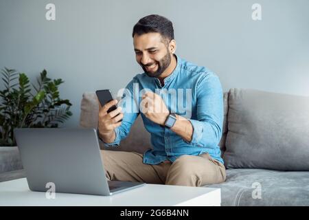 Uomo d'affari indiano gridando allegri leggere grandi notizie sullo smartphone Foto Stock