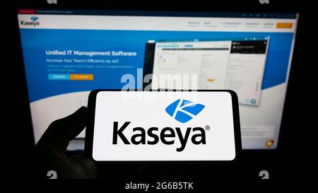 Persona che detiene uno smartphone con il logo della società americana di GESTIONE DELLA sicurezza IT Kaseya Limited sullo schermo davanti al sito Web. Mettere a fuoco il display del telefono. Foto Stock
