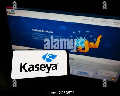 Persona che detiene il cellulare con il logo della società americana DI gestione DELLA sicurezza IT Kaseya Limited sullo schermo davanti alla pagina web. Mettere a fuoco il display del telefono. Foto Stock