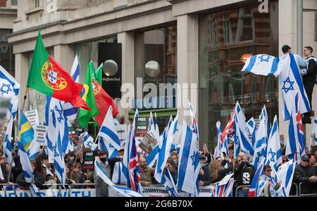 I sostenitori di pro-Israele fanno onda le bandiere, tengono i cartelli durante la protesta.i dimostranti pro-israeliani si radunano fuori dall'ambasciata israeliana ad High Street Kensington a sostegno del cessate il fuoco concordato il 21 maggio. Un piccolo gruppo di palestinesi si è rivolto contro dimostrare la manifestazione israeliana, tuttavia la polizia ha formato un cordone tra le due folle per evitare qualsiasi violenza. Foto Stock