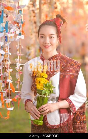 Ritratto di una donna sorridente in abiti tradizionali thailandesi con fiori, Thailandia Foto Stock
