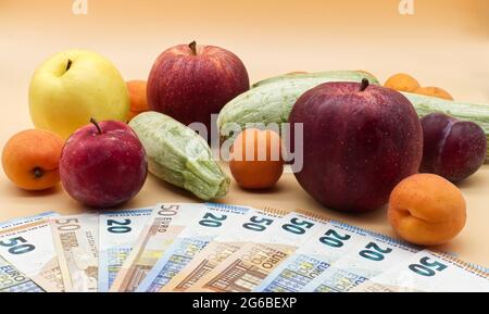 Frutta e verdura, un mucchio di banconote in euro e un mucchio di banconote in euro. Concetto di costo di frutta e verdura Foto Stock