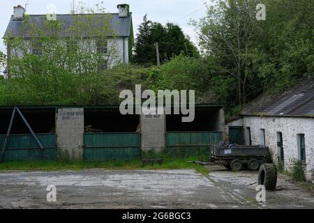 Derelict Farm con annessi, rimorchio e pneumatici per trattori di grandi dimensioni Foto Stock