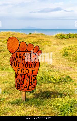 Cartello antinquinamento a forma di piede, sul sentiero di accesso alla spiaggia pubblica di Troon, Ayrshire, Scozia, Regno Unito Foto Stock