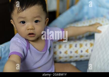 Immagine ritratto di felice stile di vita locale asiatico cinese baby giocare da solo e muoversi intorno su un lettino per bambini Foto Stock