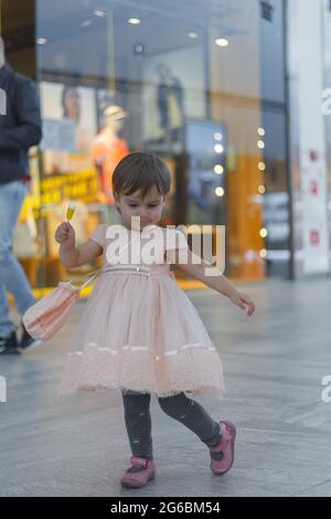 Bambino in un abito sorride, sullo sfondo di un centro commerciale. Foto Stock