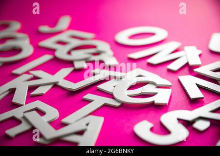 Le lettere piene miste impilano la foto in primo piano. Concetto educativo su sfondo rosa. Foto Stock
