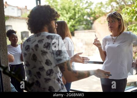 Un gruppo di giovani dipendenti in una pausa in un'atmosfera rilassata fuori dall'ufficio Foto Stock