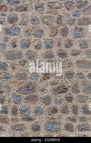 Architettura texture, dettagliate e rustiche di irregolare accoppiato muratura granito mix con piccoli fori, tradizionale... Foto Stock