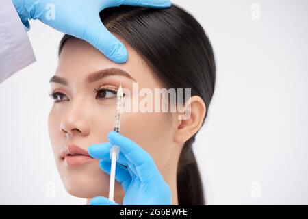 Giovane donna ottenere iniezioni viso per sollevare le sopracciglia e sbarazzarsi di rughe Foto Stock