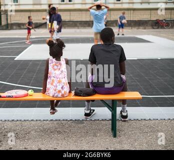 Due bambini guardano la pallacanestro nel parco giochi. Foto Stock