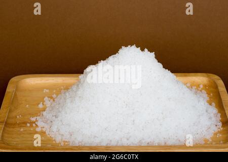 cumulo di sale marino su vassoio di legno, sale spiccano da sfondo marrone. Spazio di copia. Foto Stock