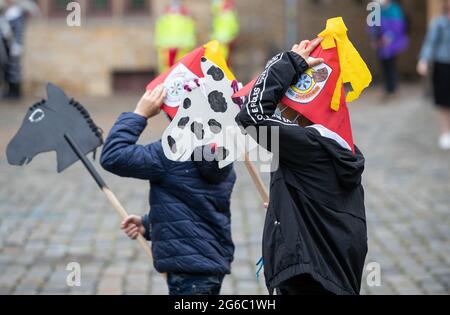 05 luglio 2021, bassa Sassonia, Osnabrück: Gli allievi della scuola primaria "cavalcano" attraverso il mercato con i loro cavalli di hobby fatti da soli. L'equitazione hobby si svolge dal 1953. L'usanza si svolge ogni anno per commemorare la Pace di Westfalia nel 1648. L'anno scorso è stato il primo anno in cui la corsa a cavallo hobby è stata annullata e doveva essere rimandata a causa della pandemia di Corona. Foto: Frito Gentsch/dpa Foto Stock