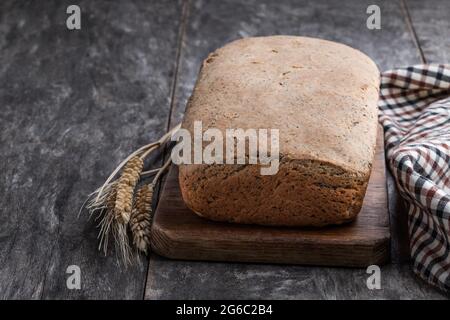 Pane integrale fatto in casa di segale con semi di sesamo su tavolo di legno Foto Stock