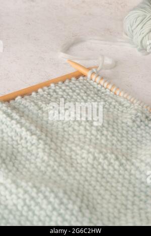 Soft Focus Light Knitting sfondo con grandi aghi in legno e lana color menta su uno sfondo in marmo con Copy Space Foto Stock