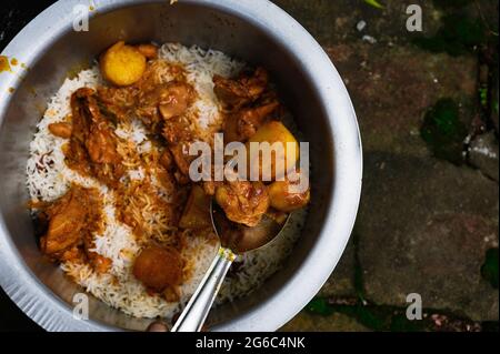 Una donna sta cucinando biryani. Biryani è una parola indo-ariana derivata dalla parola persiana 'Birian', che significa ‘fritto prima di cucinare' e 'Birinj', la parola persiana per il riso. Il Biryani è uno dei piatti più popolari e ordinati in India. È fatto con spezie indiane, riso e carne (pollo, manzo, capra, agnello, gamberetto, pesce), e talvolta, in aggiunta, uova o ortaggi, come le patate di alcune varietà regionali. Ci sono varie teorie relative all'origine di questo piatto delizioso. Molti storici credono che i biryani provenivano dalla Persia e sono stati portati in India dai Mughals. Foto Stock