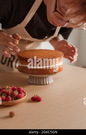 Pastry chef torta mette strato su una torta. Rendere il processo di torta Foto Stock