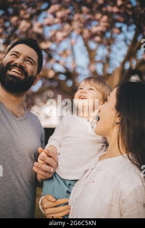 Felice giovane famiglia trascorre il tempo nel giardino fiorito. Foto Stock