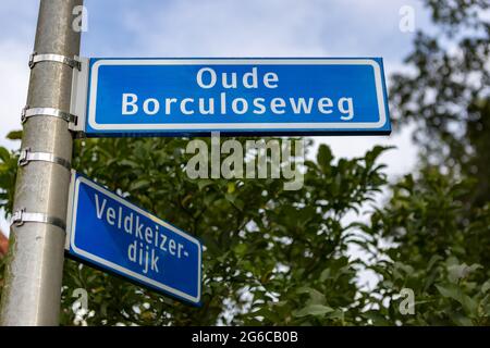 WIERDEN, OLANDA - 10 settembre 2020: Cartello stradale olandese in blu con lettera bianca contro un cielo blu con nuvole e verde sullo sfondo Foto Stock