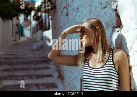 Ritratto di una bella bionda femmina che guarda via. In attesa di qualcuno in luminoso giorno di sole. Viaggio in Grecia. Foto Stock