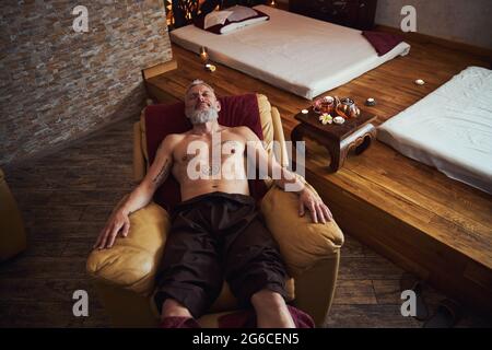 Felice uomo grizzled godendo del tempo nella spa orientale Foto Stock