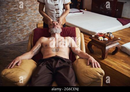 Felice tattoed maschio godendo del tempo in spa esotica Foto Stock