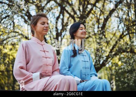 Allenatore di arti marziali rilassato con donna che medita all'esterno Foto Stock