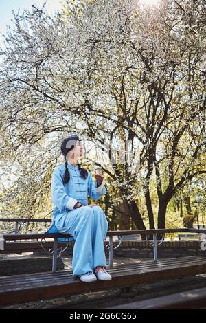 Allenatore Tai chi con tè sulla panca che guarda intorno al parco Foto Stock
