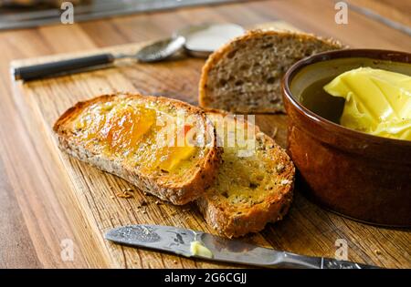 Toast al granaio con burro e marmellata per colazione su tavola di legno fotografia fatta da Simon Dack Foto Stock