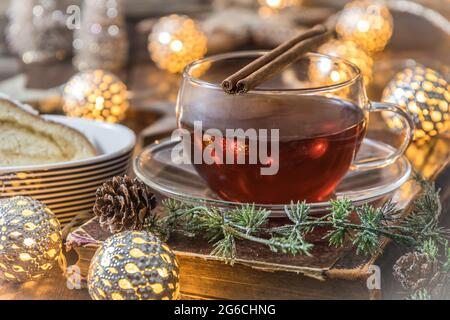 Bicchiere di tè e stollen su un tavolo di legno decorato a natale Foto Stock